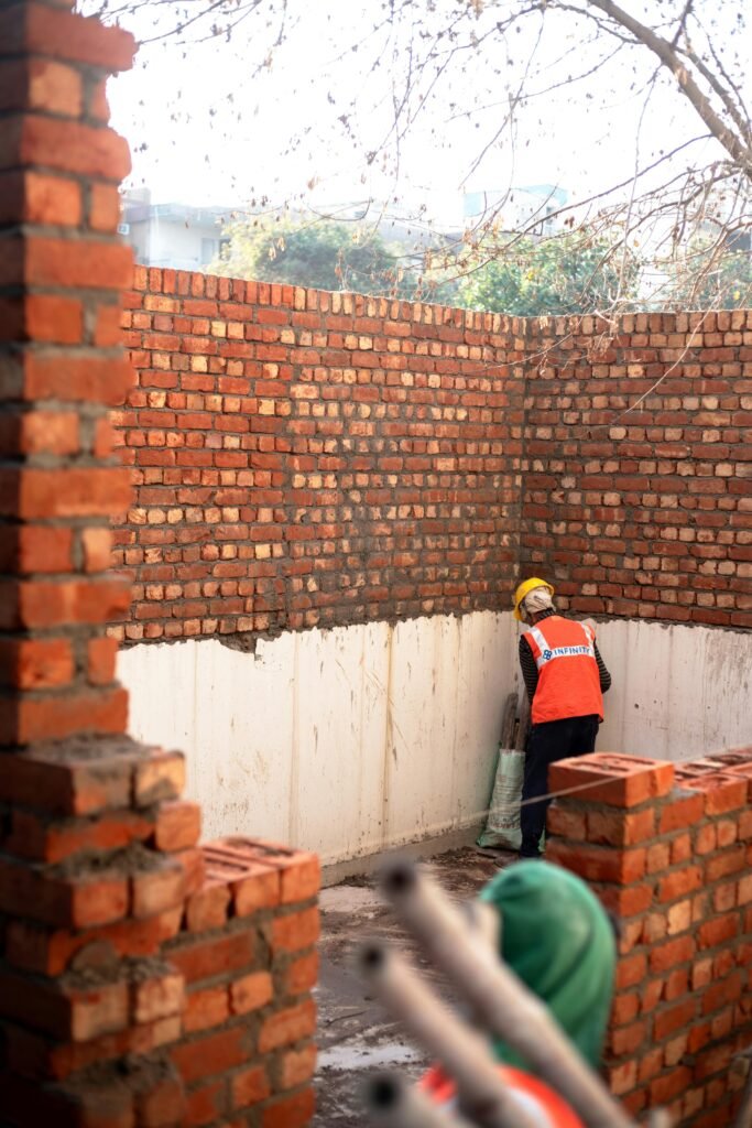 A construction worker layering bricks on a site in Delhi, India.