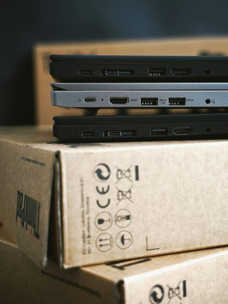 Close-up of stacked modern laptops on cardboard boxes emphasizing portable technology.