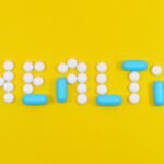 Pills spelling 'health' on a vibrant yellow background, symbolizing wellness.